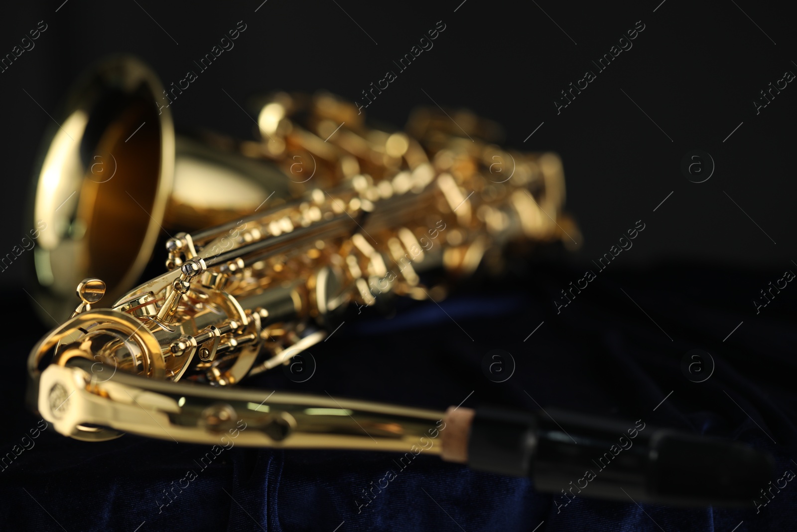 Photo of Jazz. One beautiful saxophone on dark blue fabric, closeup. Space for text