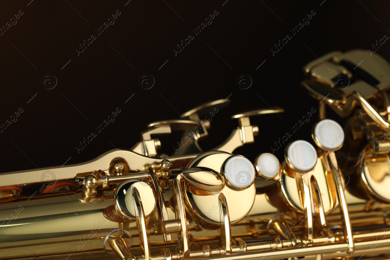 Photo of Jazz. One beautiful saxophone on brown background, closeup