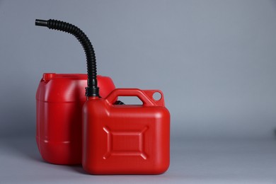 Photo of Two red plastic canisters on light grey background, space for text