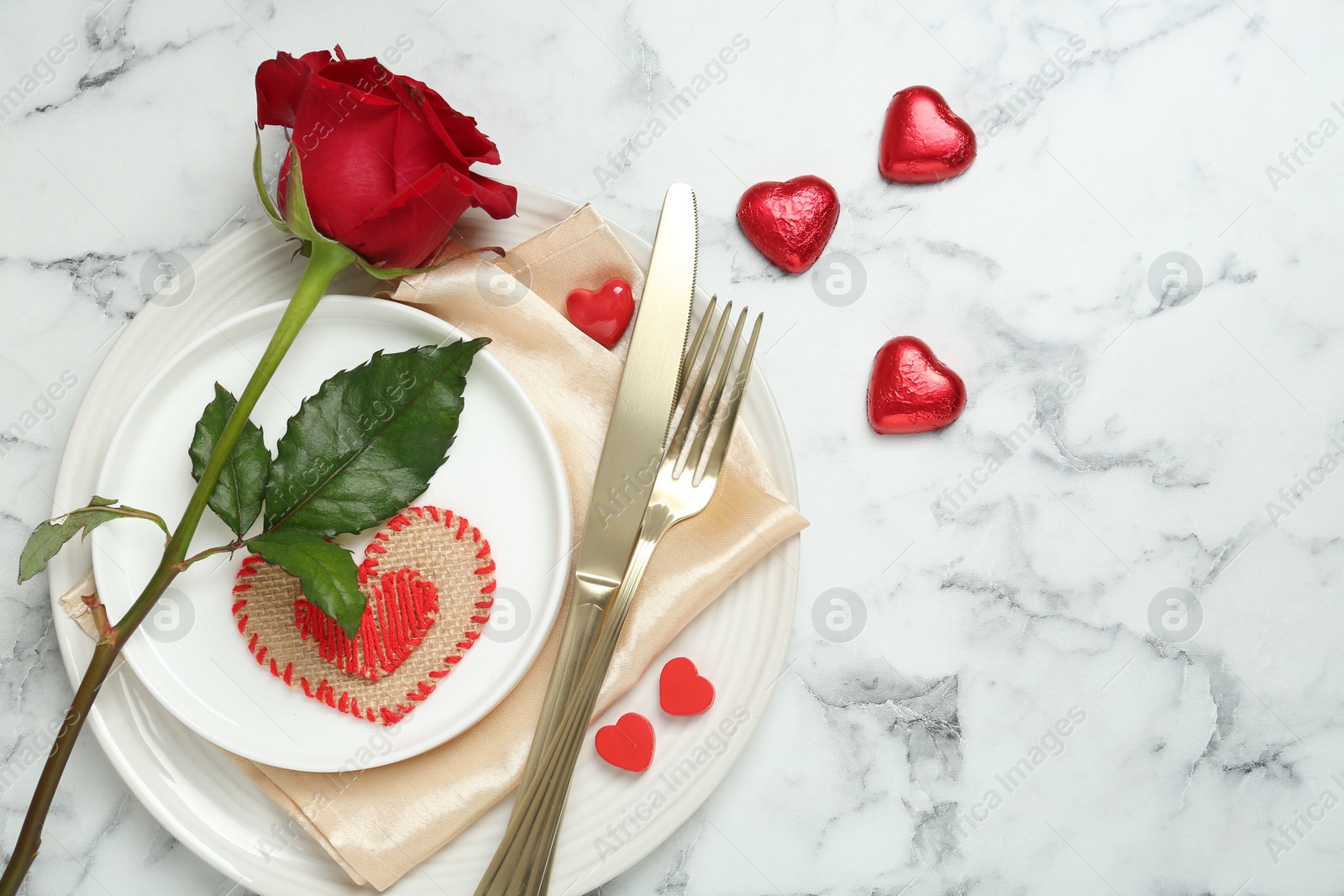 Photo of Romantic place setting for Valentine's day. Tableware, cutlery, rose and decorative hearts on white marble table, flat lay. Space for text