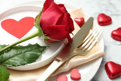 Photo of Romantic place setting for Valentine's day. Rose, tableware, cutlery and decorative hearts on white table, closeup