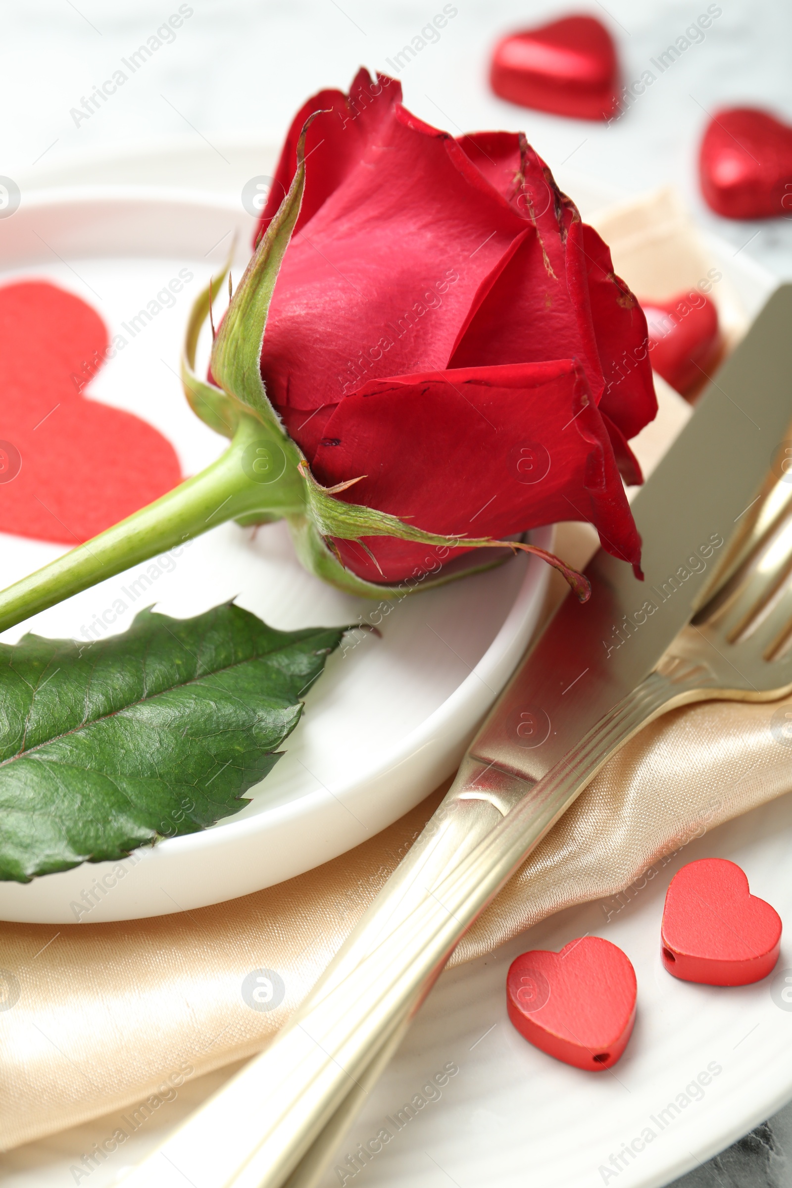 Photo of Romantic place setting for Valentine's day. Rose, tableware, cutlery and decorative hearts on white table, closeup