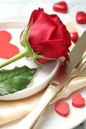 Photo of Romantic place setting for Valentine's day. Rose, tableware, cutlery and decorative hearts on white table, closeup