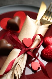 Photo of Romantic place setting for Valentine's day. Tableware, cutlery and candies in shape of hearts on grey table, closeup