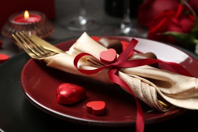 Photo of Romantic table setting for Valentine's day. Cutlery, candies and decorative hearts on plate, closeup