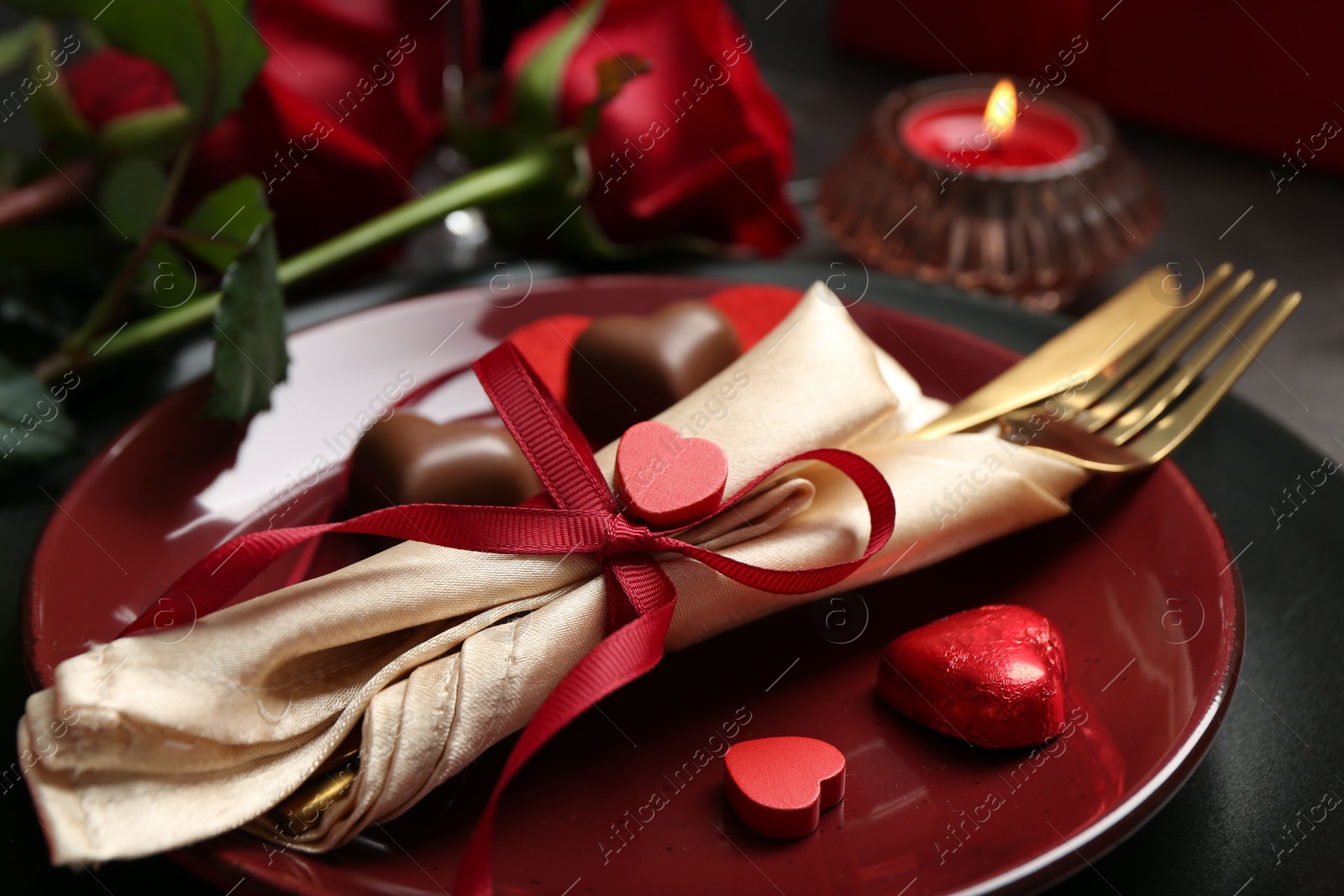 Photo of Romantic place setting for Valentine's day. Tableware, cutlery, candies and decorative hearts on grey table, closeup