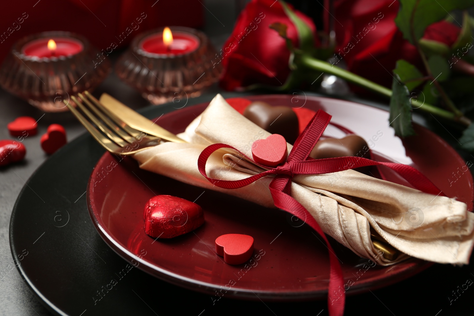 Photo of Romantic place setting for Valentine's day. Tableware, cutlery, candies and decorative hearts on grey table, closeup