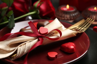 Photo of Romantic table setting for Valentine's day. Cutlery, candies and decorative hearts on plate, closeup