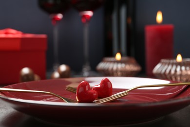 Romantic place setting for Valentine's day. Forks with decorative hearts and plate on table, closeup