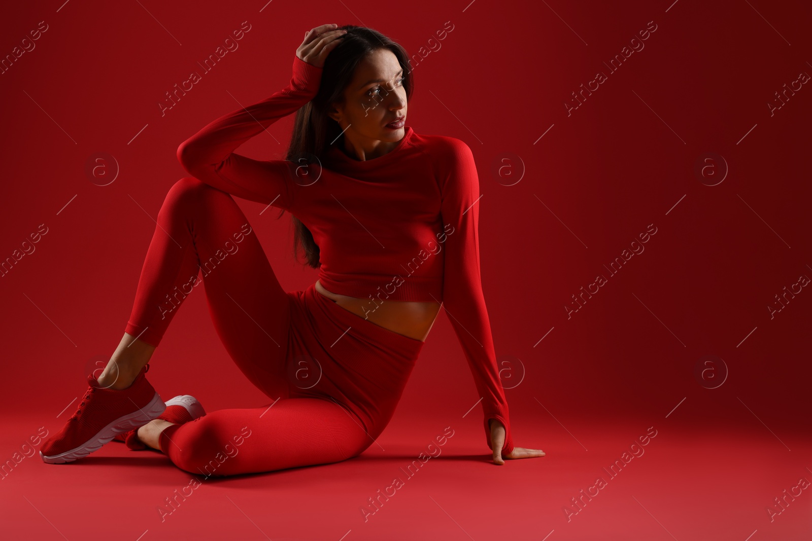 Photo of Beautiful woman in stylish sportswear on red background