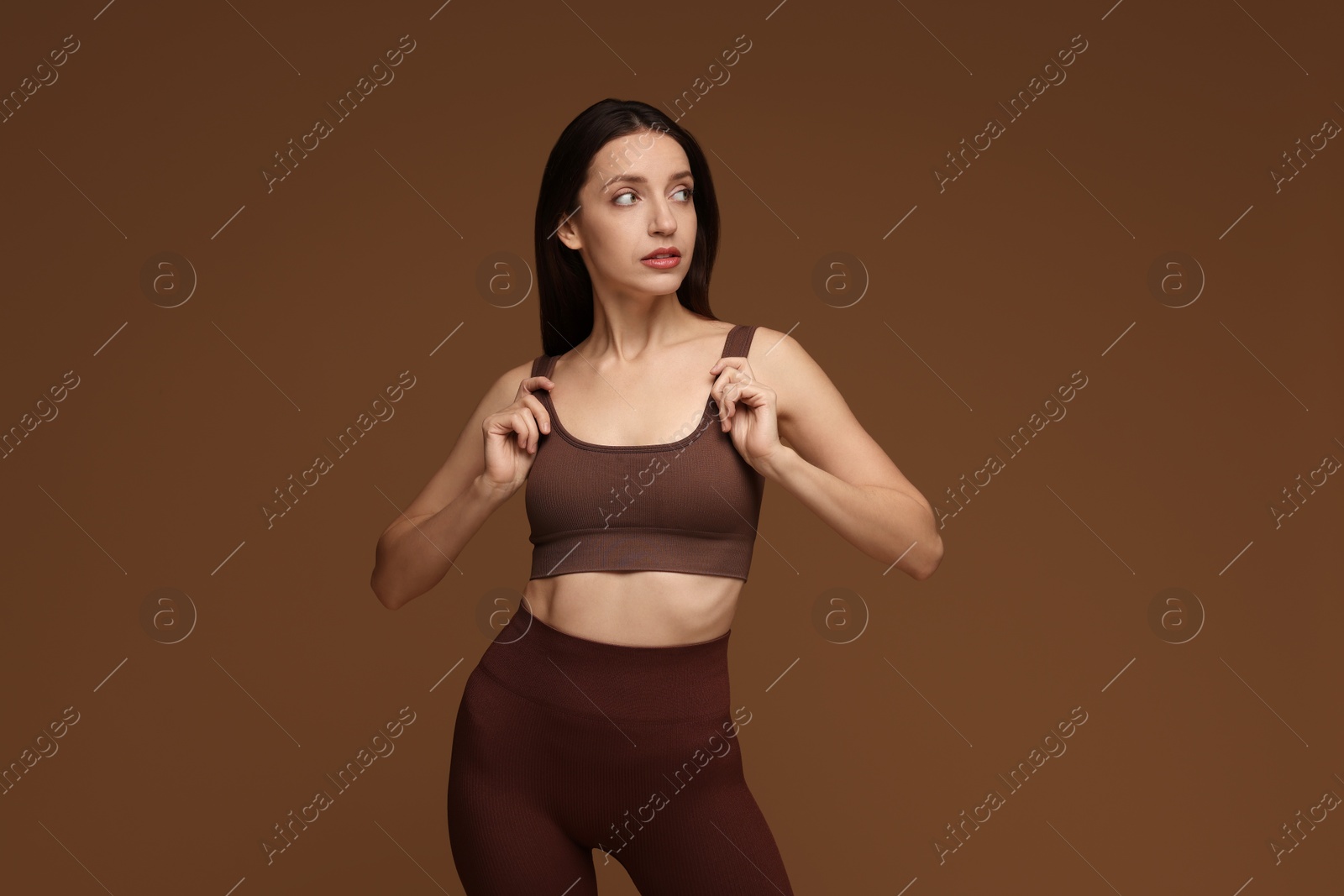 Photo of Beautiful woman in stylish sportswear on brown background