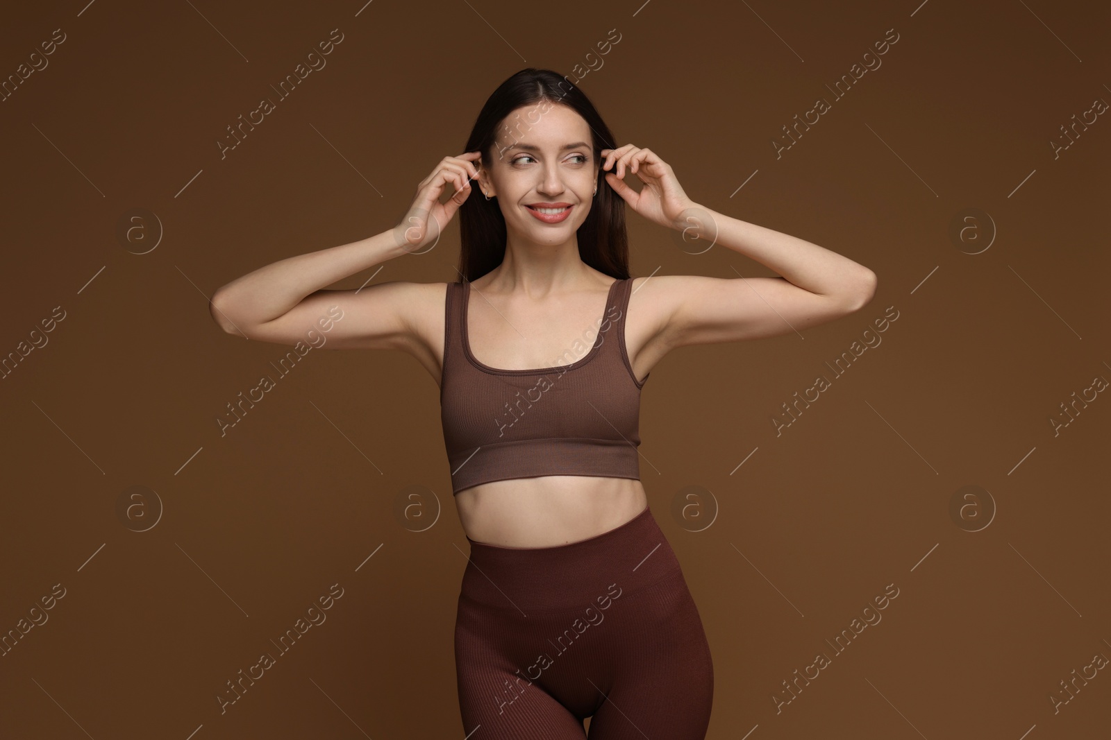 Photo of Beautiful woman in stylish sportswear on brown background