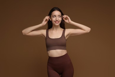 Photo of Beautiful woman in stylish sportswear on brown background