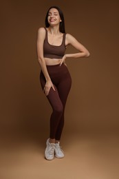 Photo of Beautiful woman in stylish sportswear on brown background