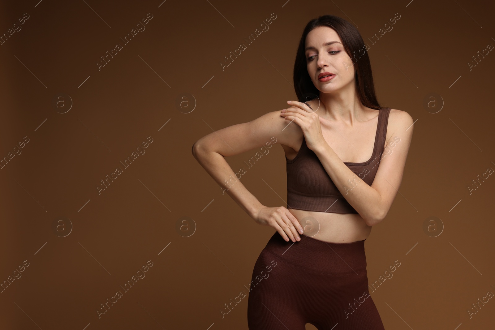 Photo of Beautiful woman in stylish sportswear on brown background. Space for text