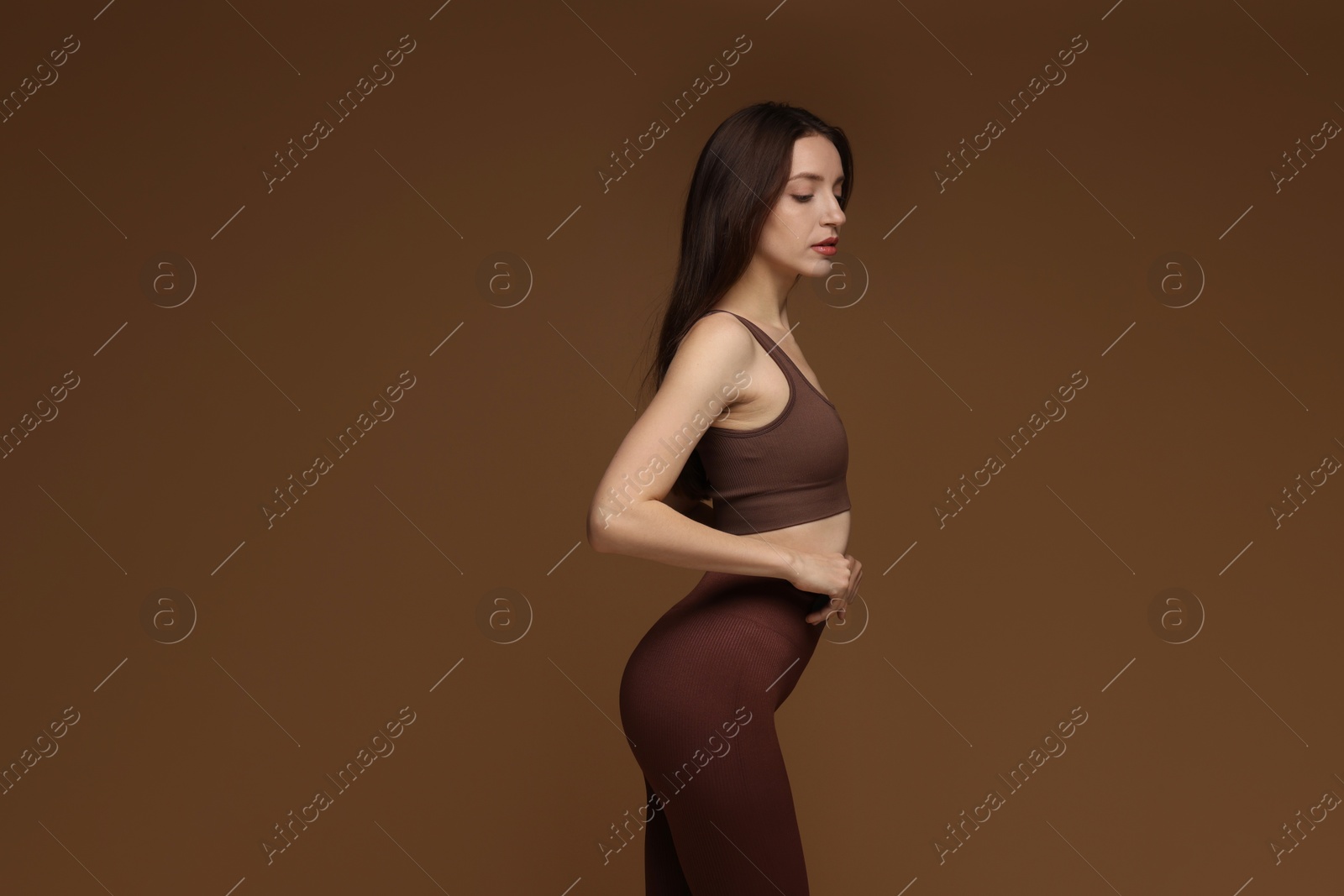 Photo of Beautiful woman in stylish sportswear on brown background. Space for text