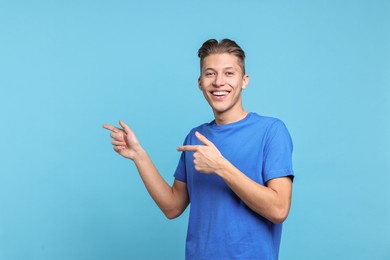 Photo of Happy man welcoming friends or guests on light blue background. Space for text