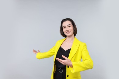 Photo of Happy businesswoman welcoming clients or partners on light grey background