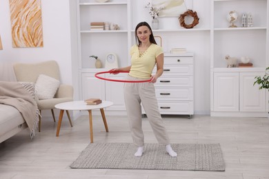 Photo of Smiling woman training with hula hoop at home