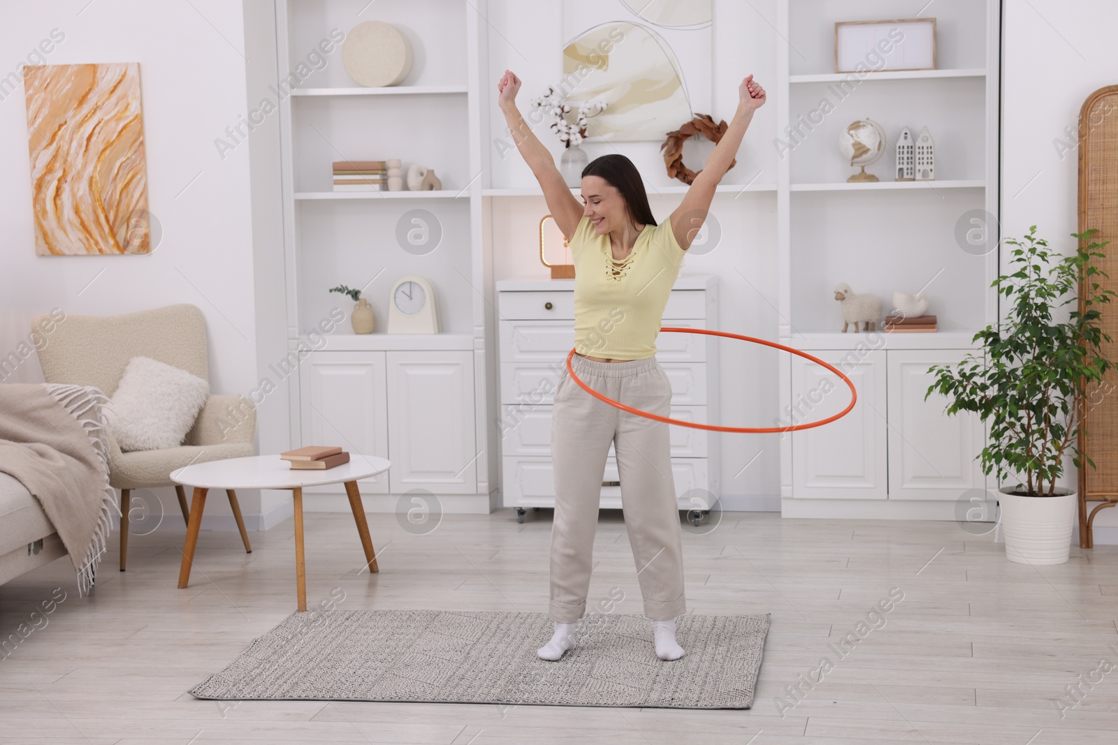 Photo of Smiling woman training with hula hoop at home