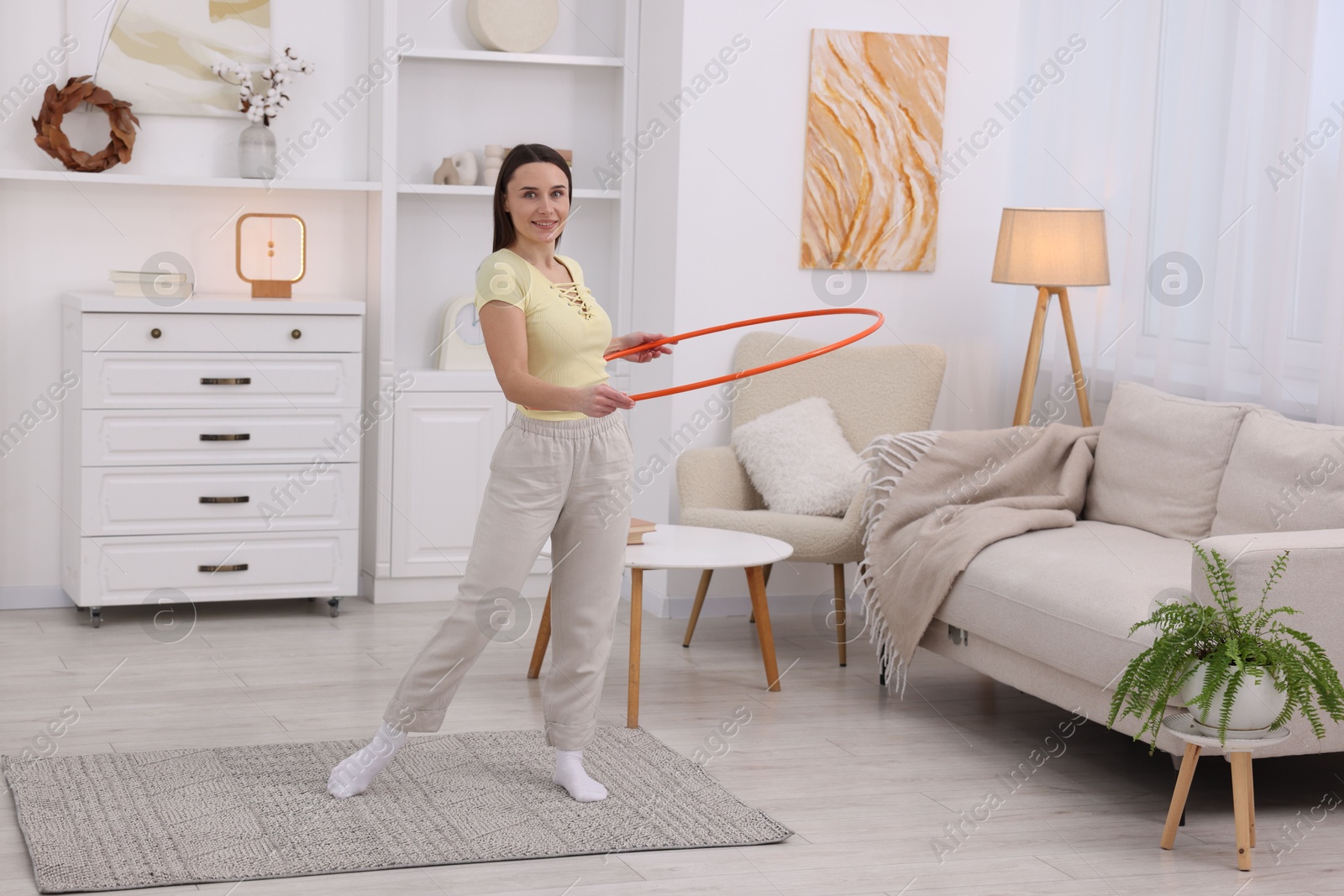 Photo of Smiling woman training with hula hoop at home