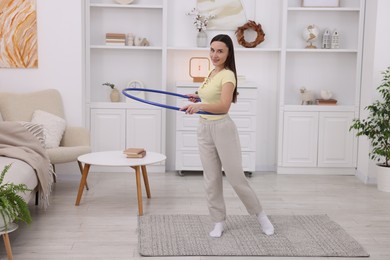 Photo of Smiling woman training with hula hoop at home