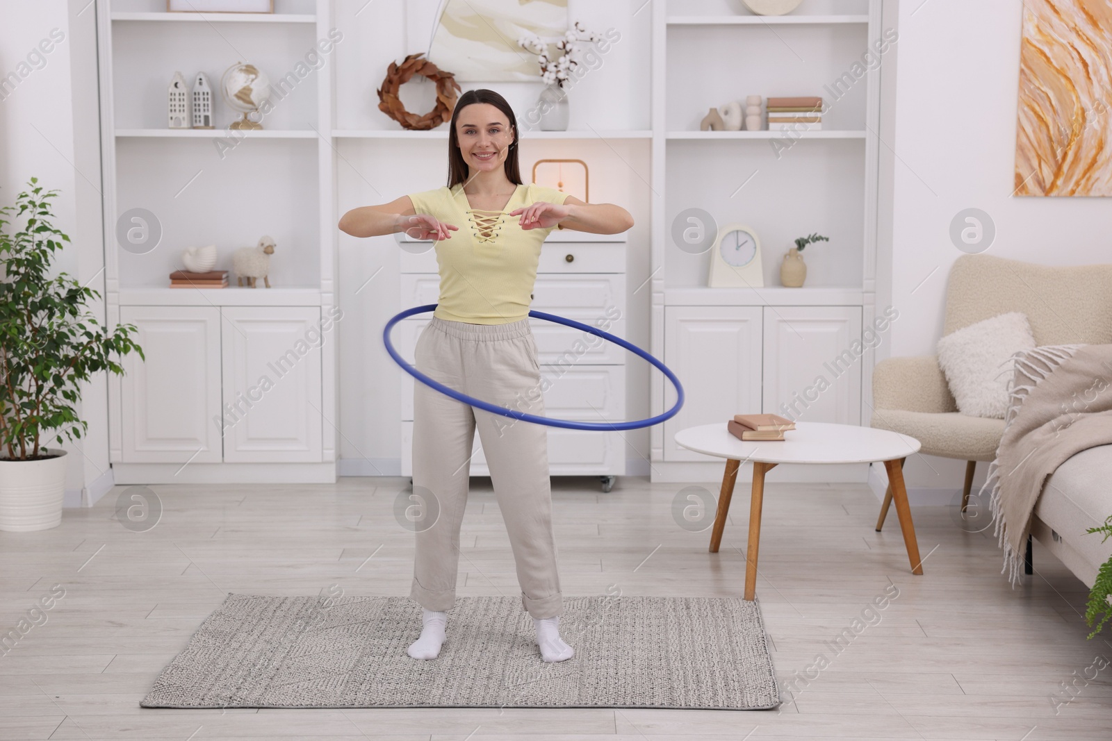 Photo of Smiling woman training with hula hoop at home