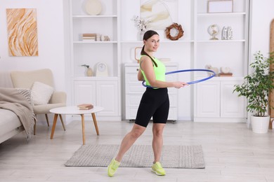 Photo of Smiling woman training with hula hoop at home