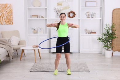 Photo of Smiling woman training with hula hoop at home