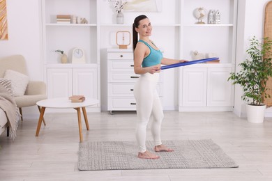 Photo of Smiling woman training with hula hoop at home