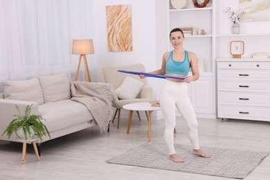 Photo of Smiling woman training with hula hoop at home