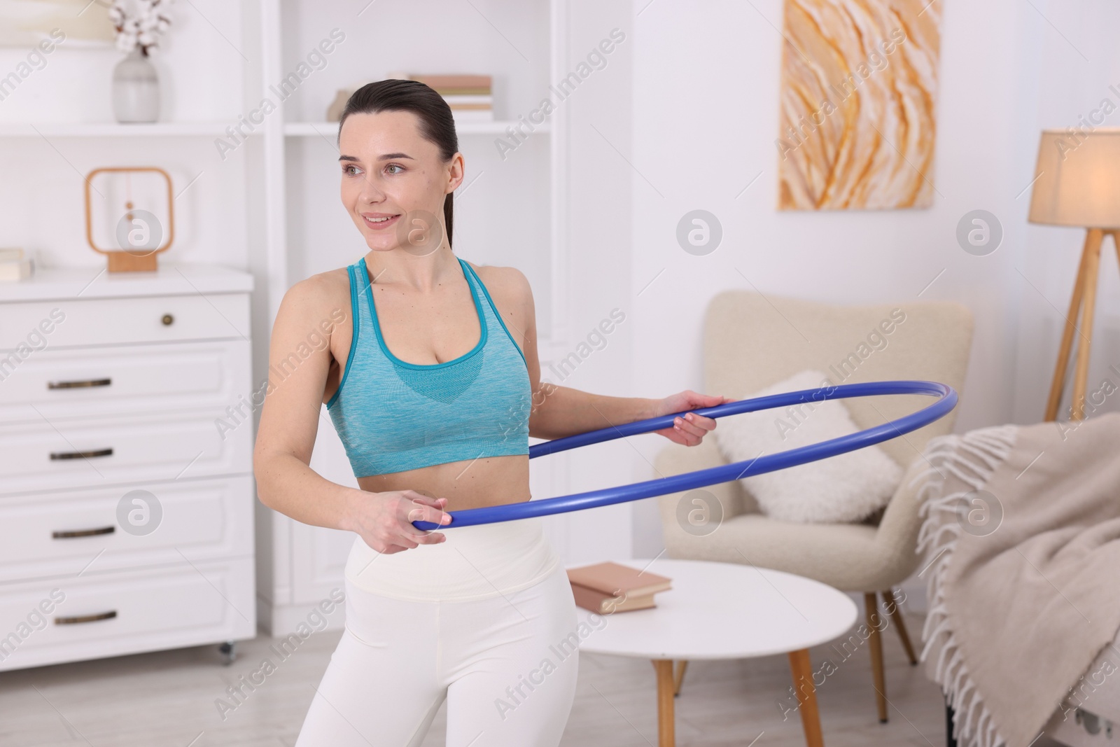 Photo of Smiling woman training with hula hoop at home