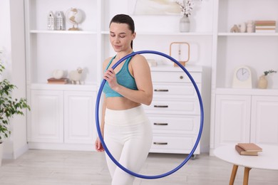 Photo of Beautiful woman with hula hoop at home