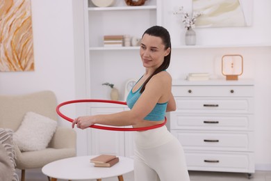 Photo of Smiling woman training with hula hoop at home