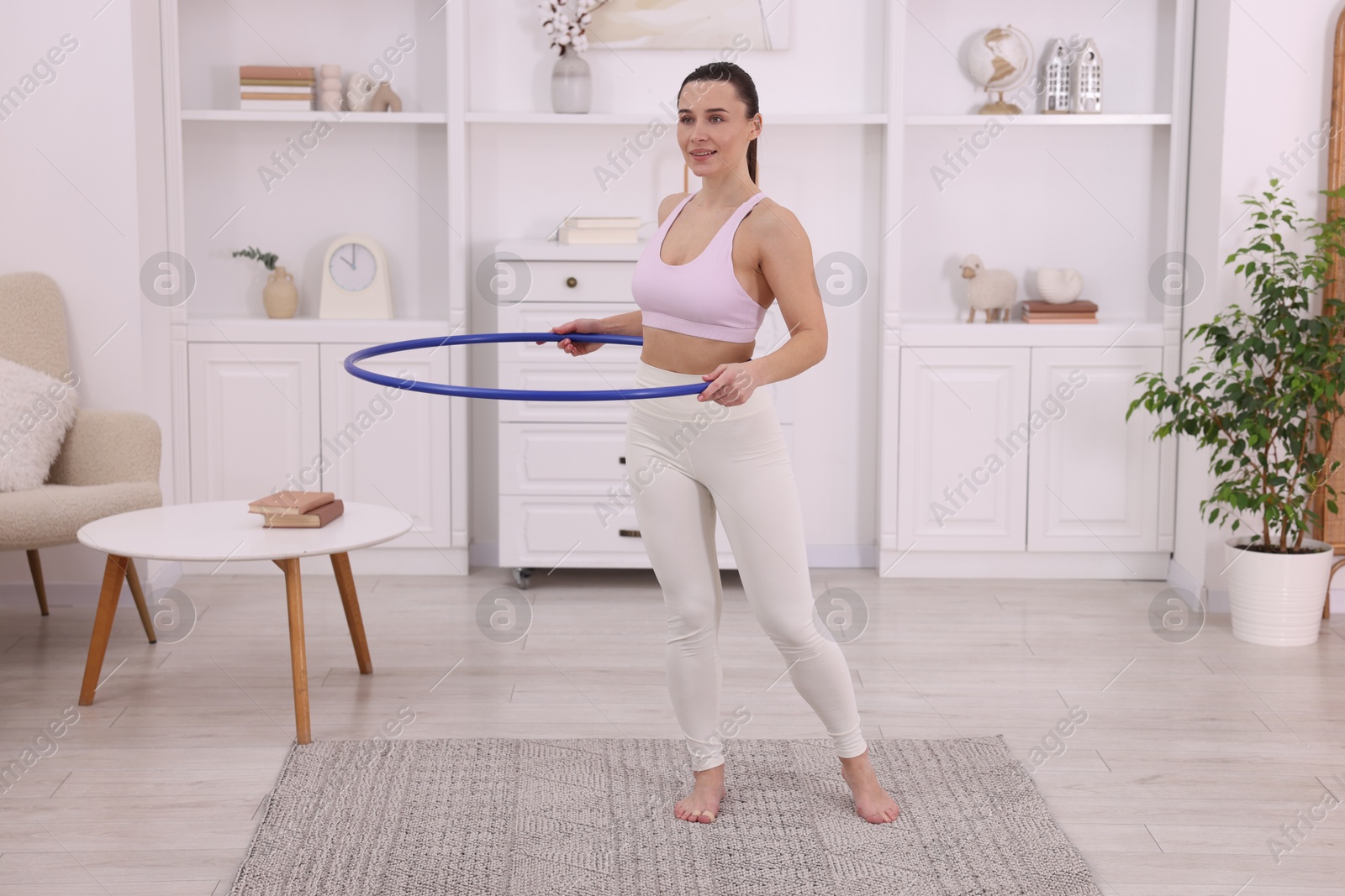 Photo of Smiling woman training with hula hoop at home