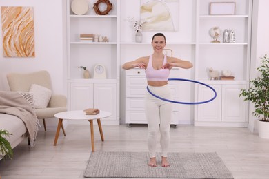 Photo of Smiling woman training with hula hoop at home