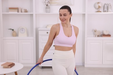 Photo of Smiling woman with hula hoop at home