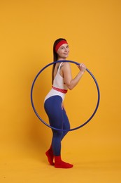 Photo of Smiling woman with hula hoop on orange background