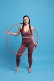 Photo of Smiling woman with hula hoop on light blue background