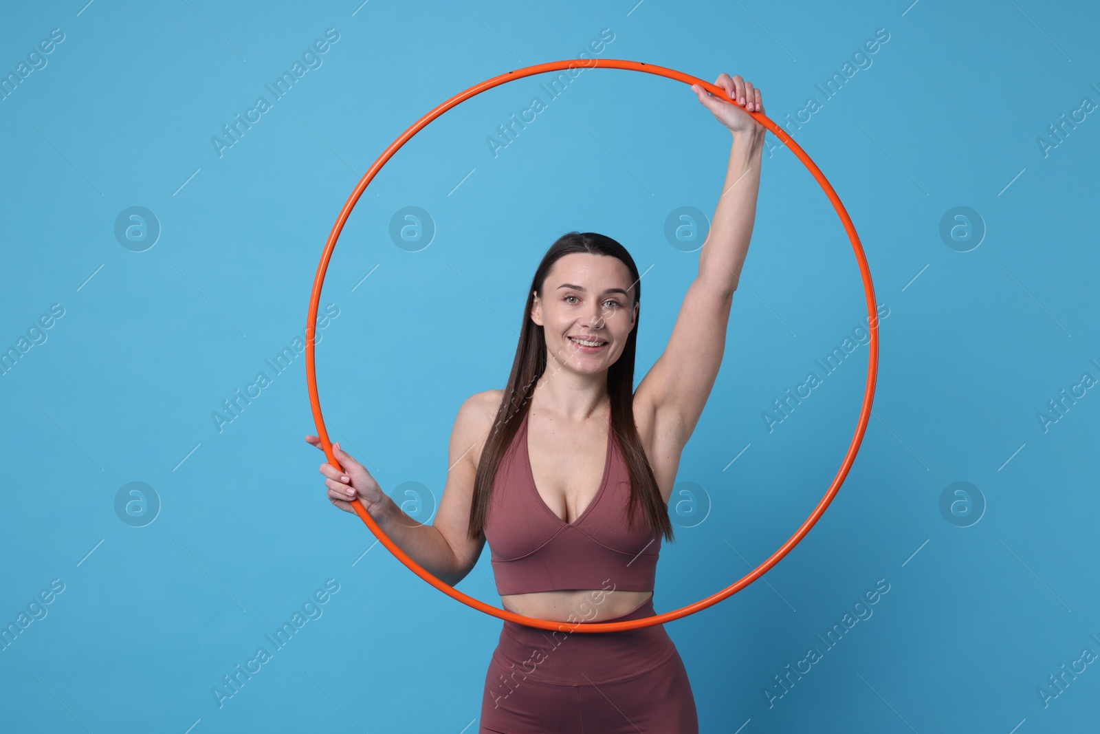 Photo of Smiling woman with hula hoop on light blue background