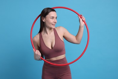 Photo of Smiling woman with hula hoop on light blue background