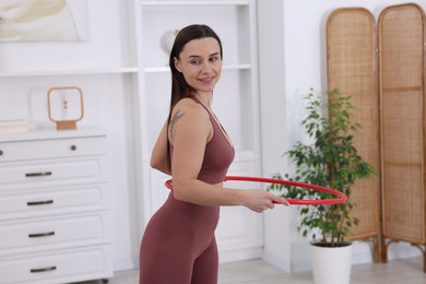 Photo of Smiling woman training with hula hoop at home