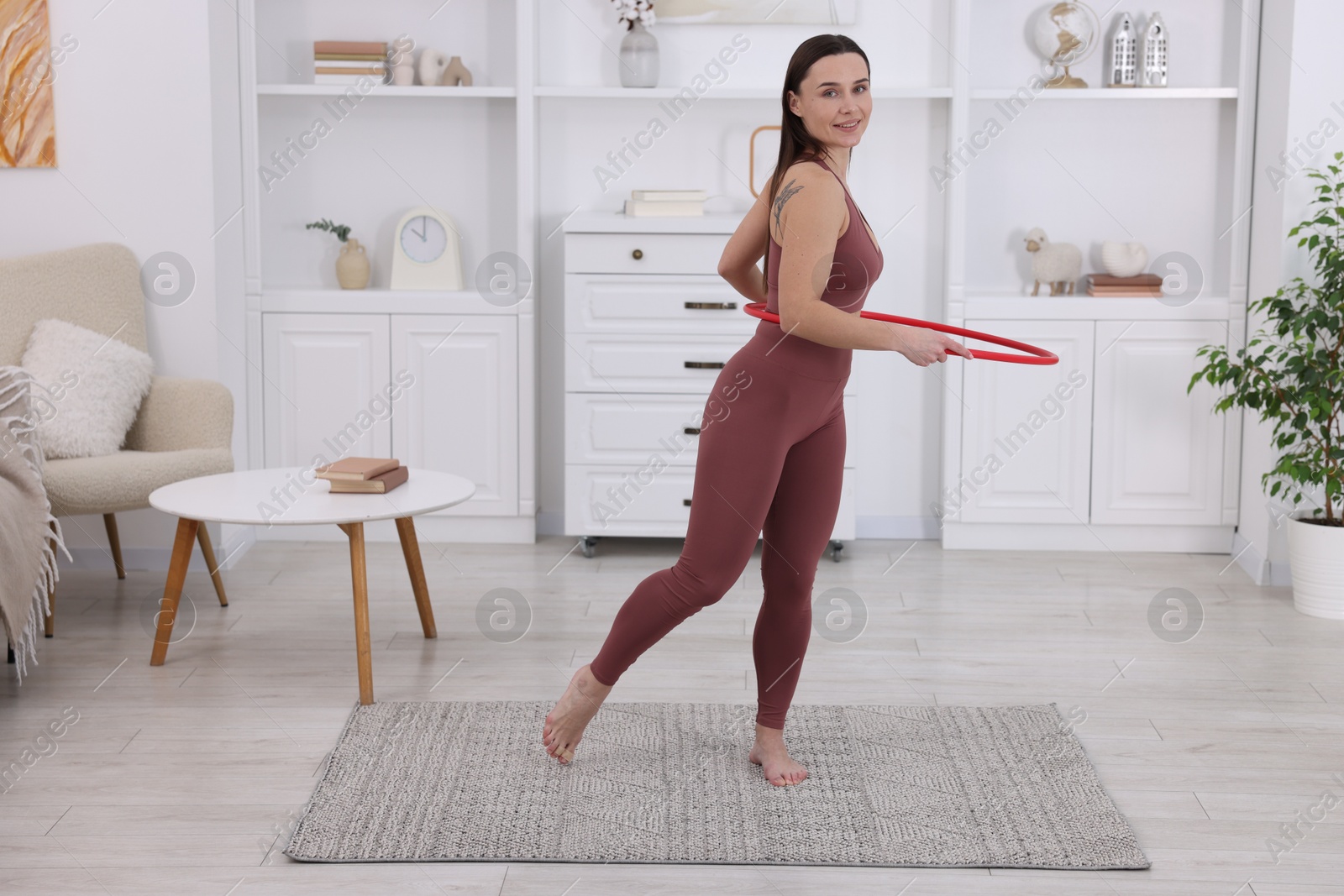 Photo of Smiling woman training with hula hoop at home