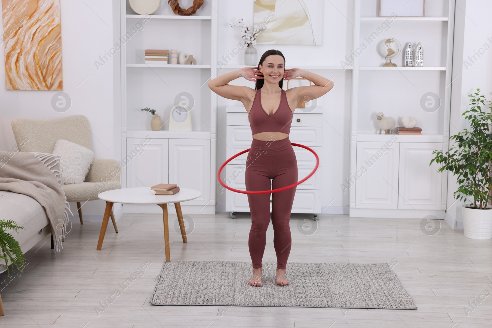 Photo of Smiling woman training with hula hoop at home