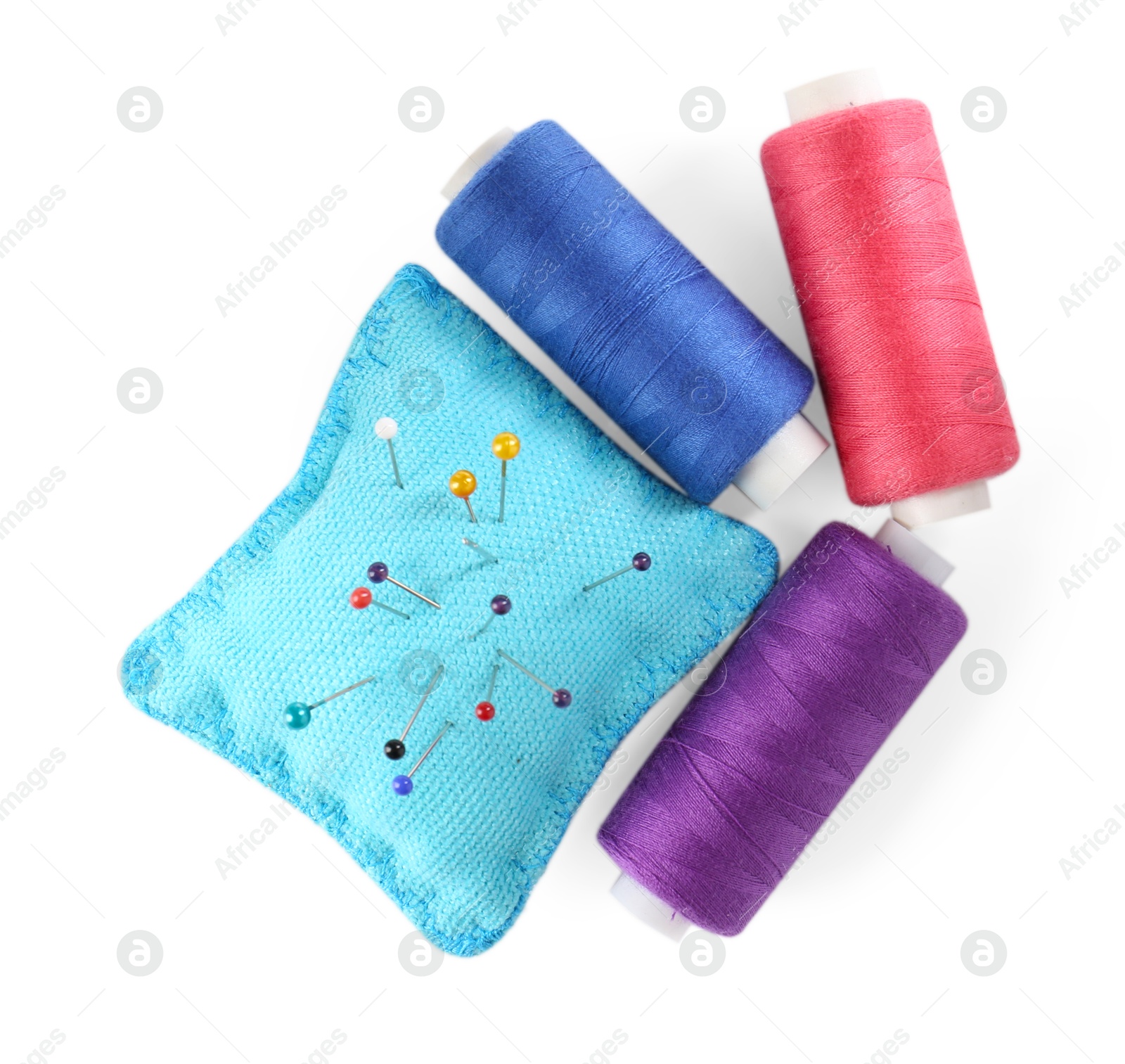 Photo of Pins, cushion and spools of thread isolated on white, top view. Sewing supplies