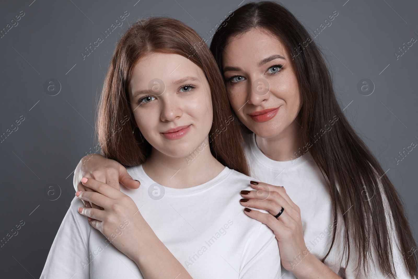 Photo of Portrait of beautiful mother with teenage daughter on grey background