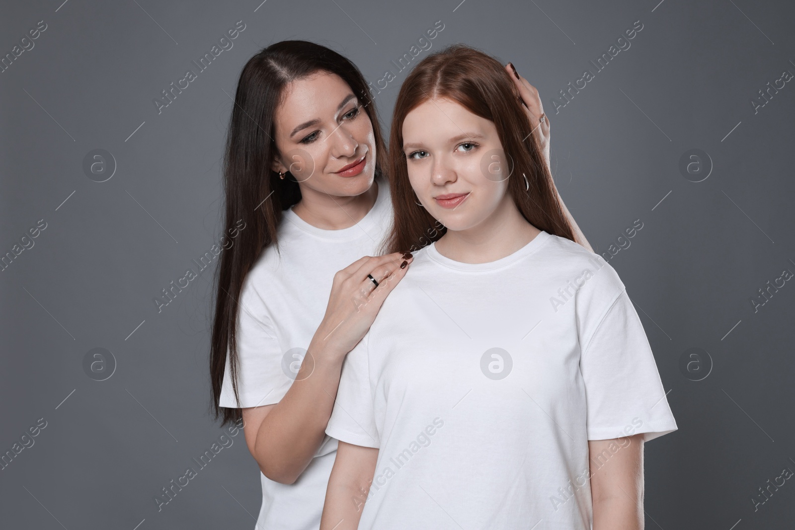 Photo of Portrait of beautiful mother with teenage daughter on grey background