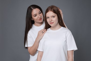 Photo of Portrait of beautiful mother with teenage daughter on grey background