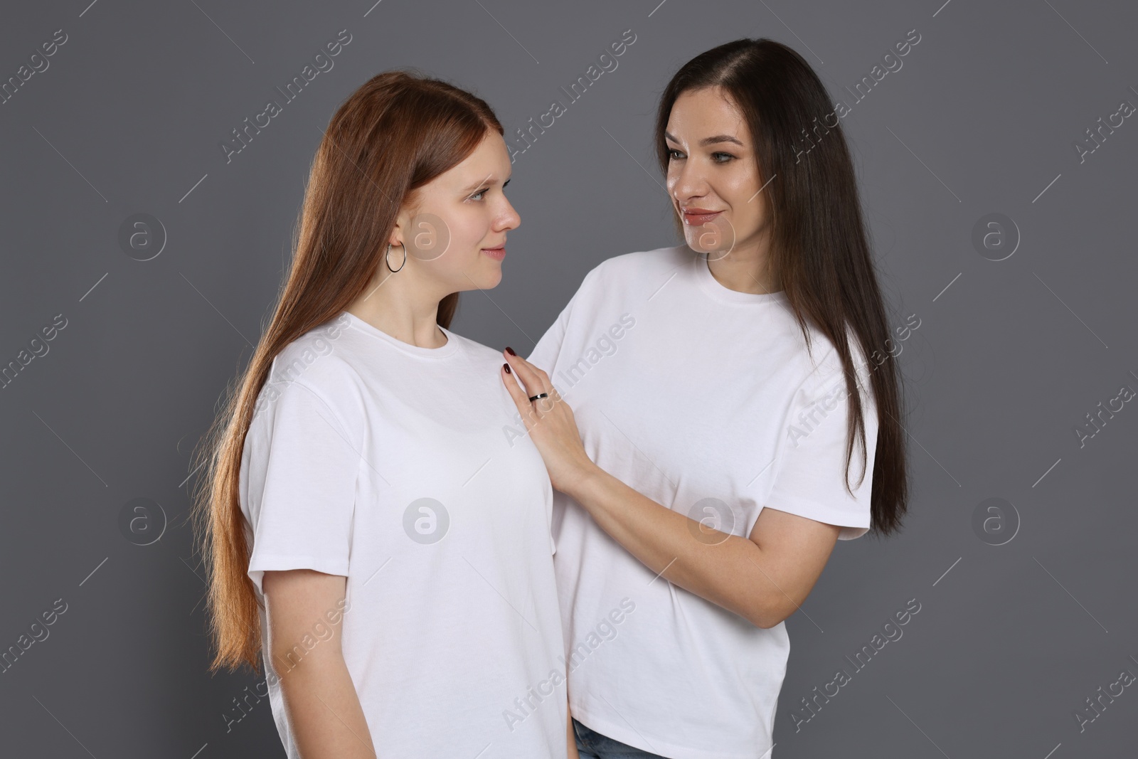 Photo of Portrait of beautiful mother with teenage daughter on grey background