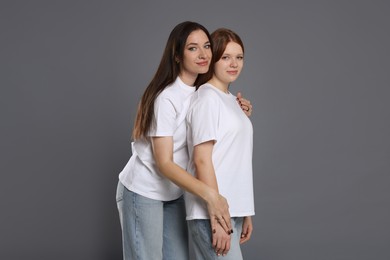 Photo of Family portrait of beautiful mother with teenage daughter on grey background, space for text